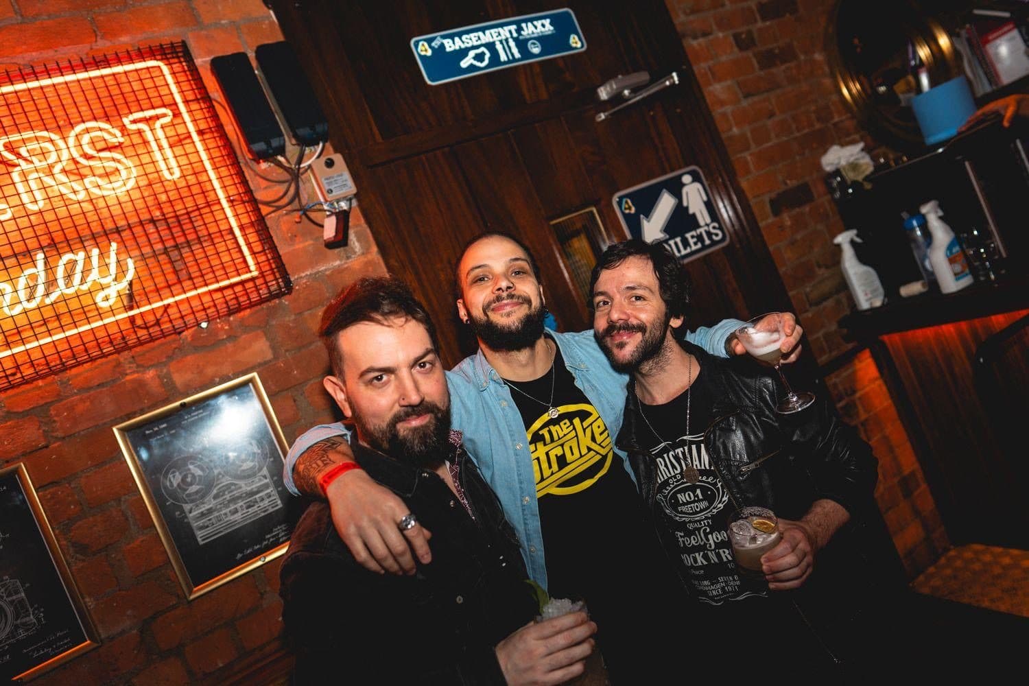 Ikke, Guto and Wagner with cocktails at 4 Dame Lane, Dublin, neon signage and bare brick behind them.