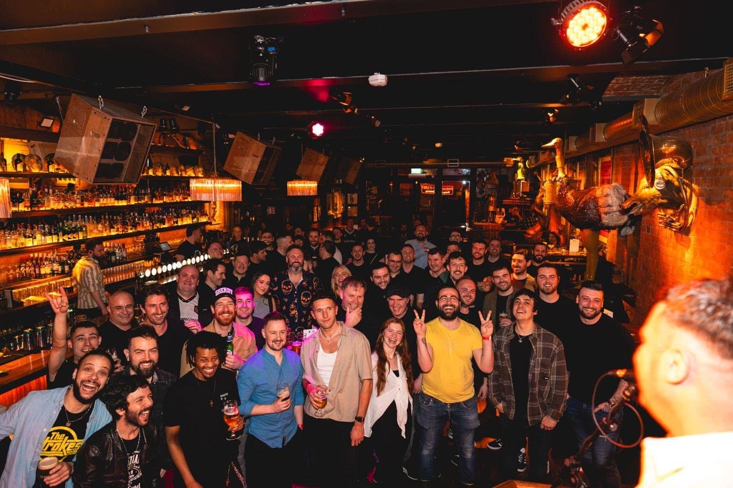 A bar packed wall to wall on a quiz night, everyone facing the host.