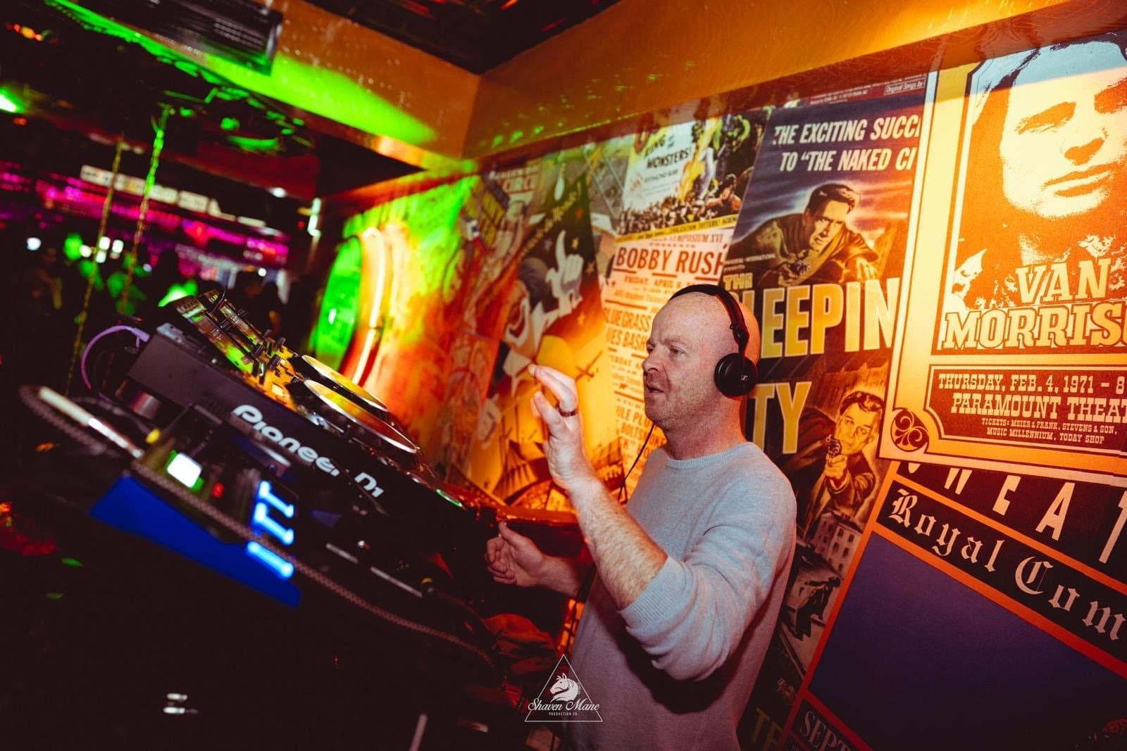 A DJ mixing on stage under red light.