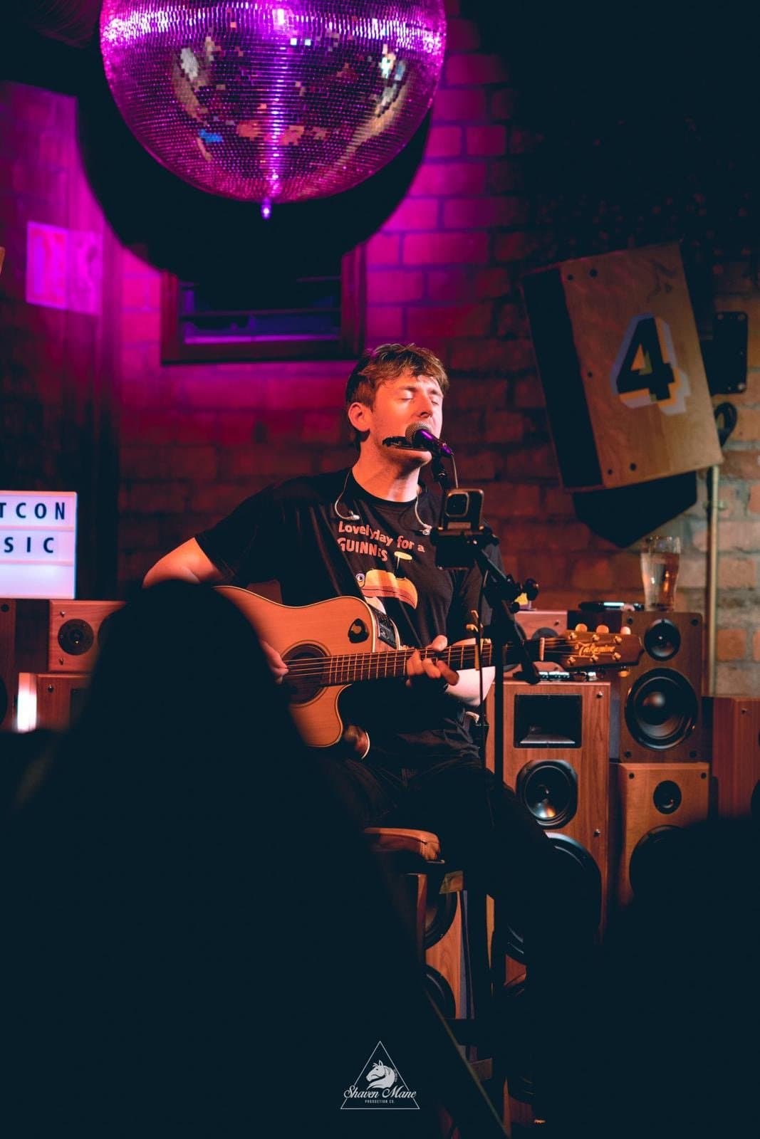 A solo artist singing and playing acoustic guitar.