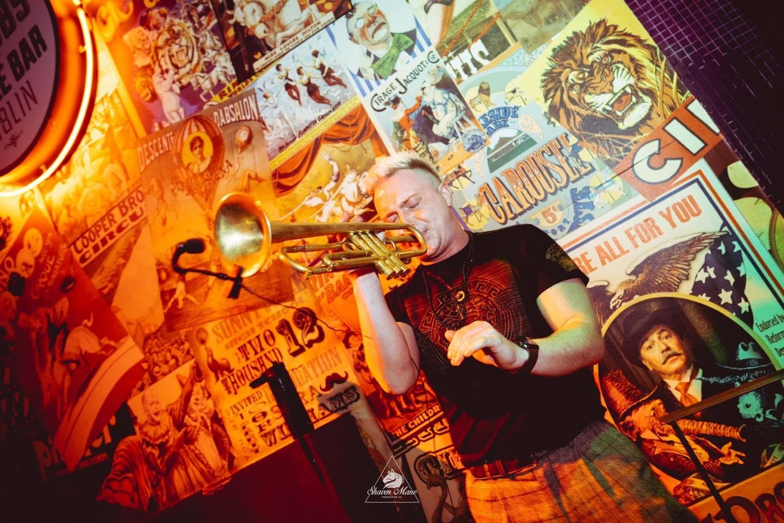 A horn player performing live in a venue.